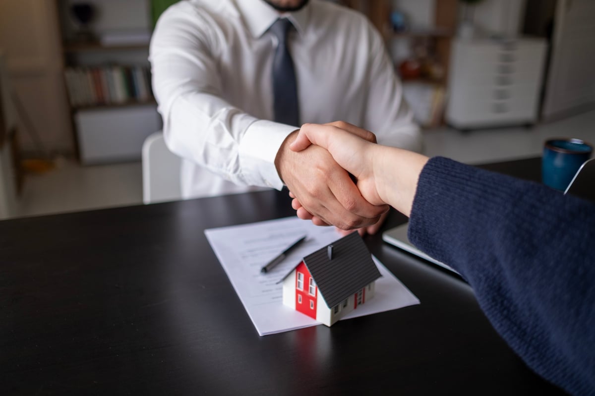 Real estate agents shake hands after signing agreement